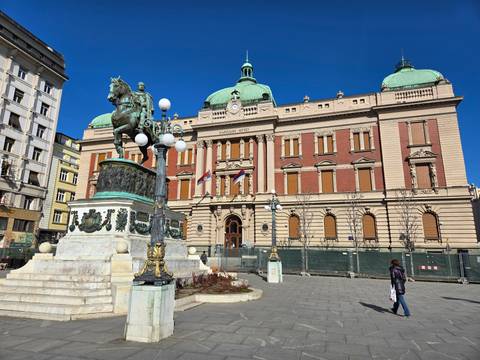       Statue and historic building in a plaza.
  