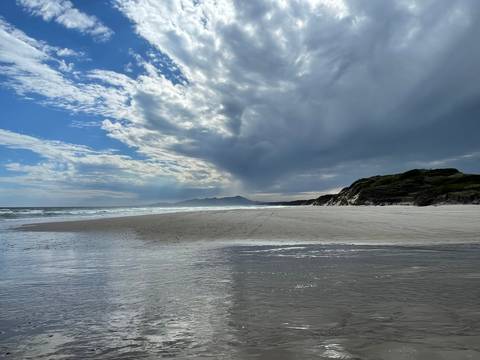 Sandy beach with a dramatic cloudy sky and ocean view.