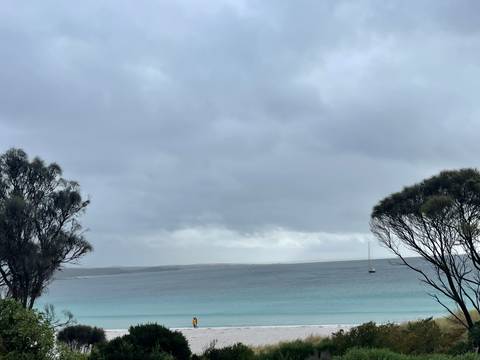       Ocean view with a distant sailboat under a cloudy sky.
  