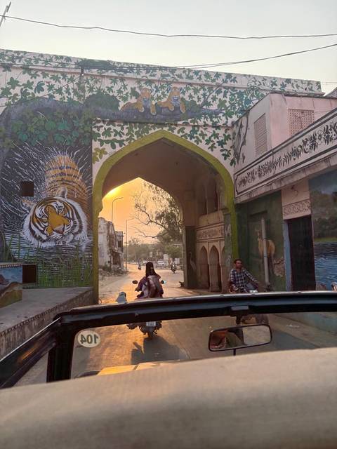 People traveling through a decorative gate at sunset.