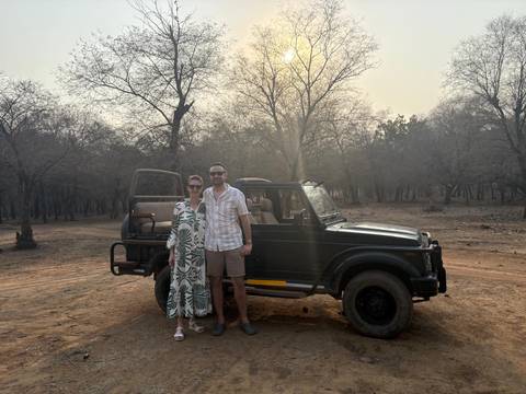Couple standing next to a jeep in a forest park.