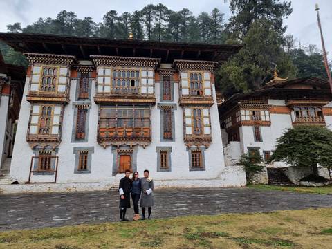       Group standing in front of a traditional Bhutanese building.
  