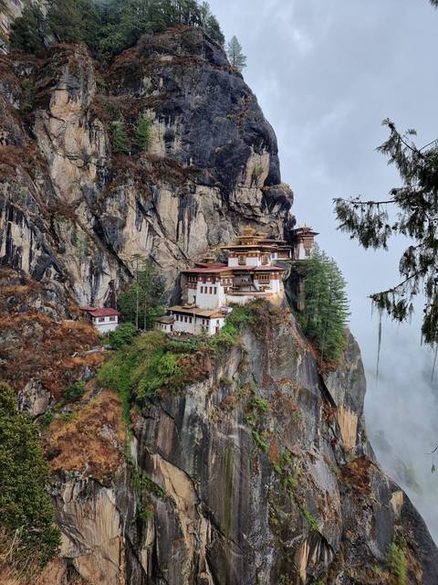       Taktshang Monastery perched on a cliff with fog rolling in.
  