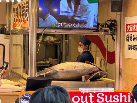 Man working inside a seafood market with a giant fish.
