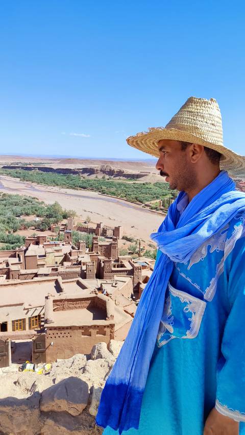       Person in traditional attire looking over Ait Benhaddou.
  