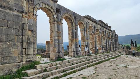       Ruins with arches and mountainous backdrop.
  