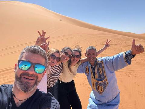 Group of people posing in the desert with sand dunes.