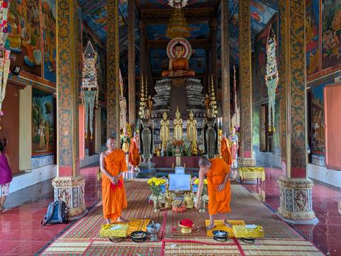 Monks in an ornate temple with religious statues.