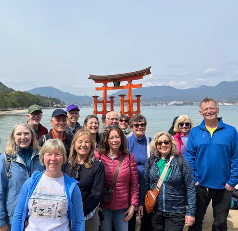 Group photo in front of a Torii gate by the sea.