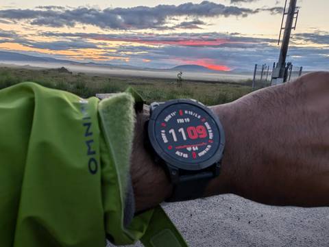Close-up of a watch displaying time against a scenic backdrop.