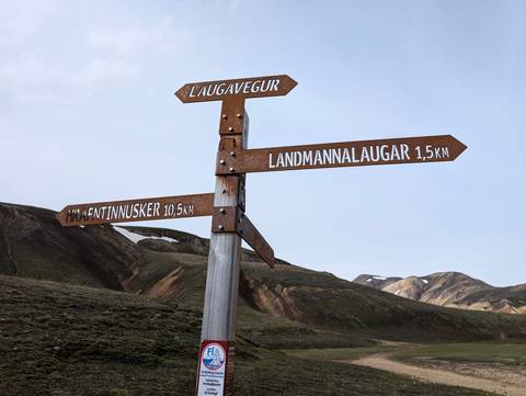 Signpost with directions to Landmannalaugar in a scenic mountain landscape.