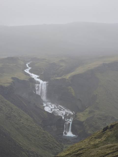 Aerial view of a cascading waterfall in a misty landscape.