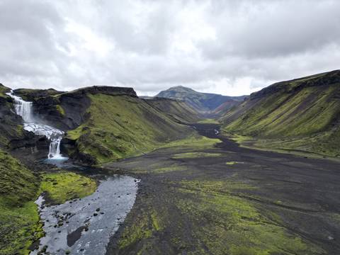 Expansive view of a valley with waterfalls and lush greenery.