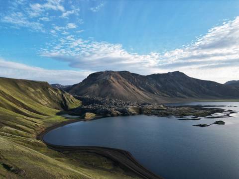 Calm lake surrounded by mountains and clear sky.