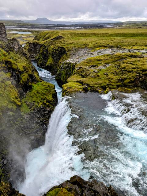 Picturesque waterfall flowing through rocky terrain with lush vegetation.