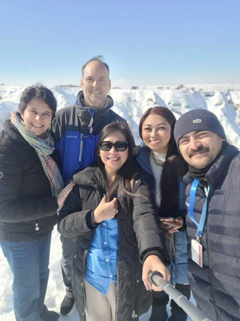 Group selfie of people in winter clothing with a snowy background.