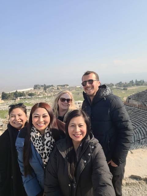 Group of people posing with historical ruins in the background.