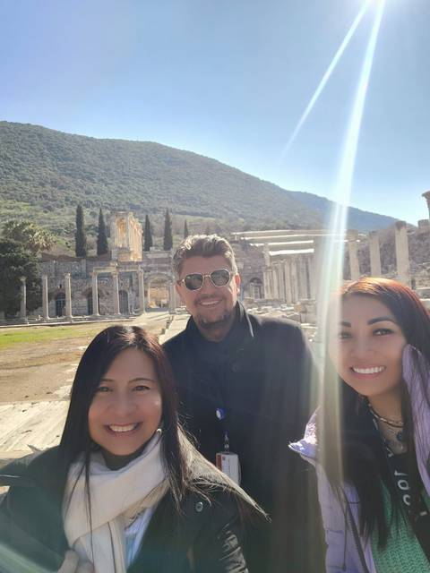 Group photo with ancient ruins and a clear sky.