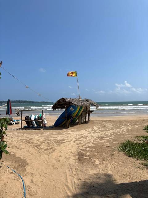       A sunny beach with surfboards and a flag.
  