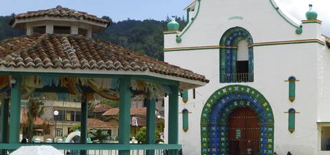 Colorful building facade in a village with hilly backdrop.