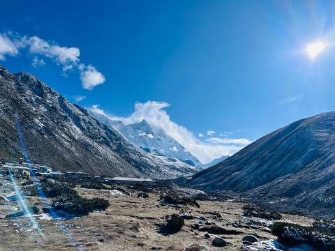 Sunny valley view with mountains under a clear blue sky.