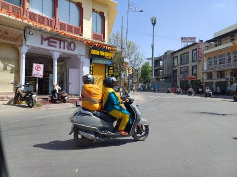 Two people on a scooter in a city street.