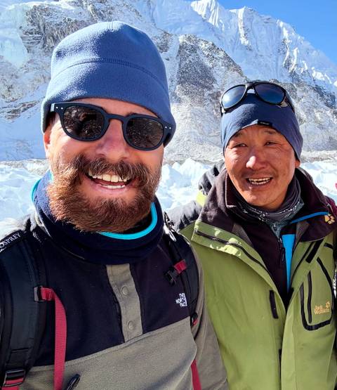 Two smiling men in winter gear with snowy background.