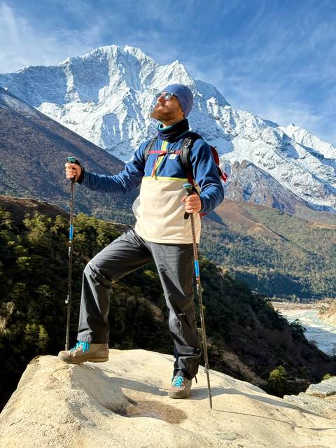 Hiker in front of snow-capped mountains with poles.