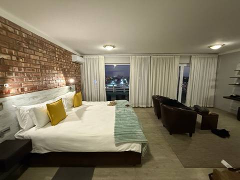       Cozy hotel room with a large bed, window view, and soft lighting.
  