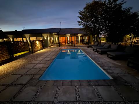       Poolside area of a lodge at dusk with ambient lights.
  