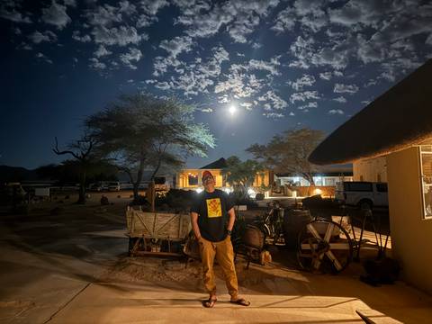      Person standing beneath a moonlit sky at a lodge.
  