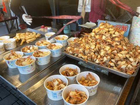       Assortment of fried seafood in bowls at a food stall.
  