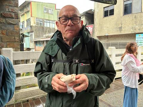       Person holding a wrapped snack with buildings in the background.
  