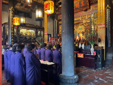       People praying inside a temple with rich decorations.
  