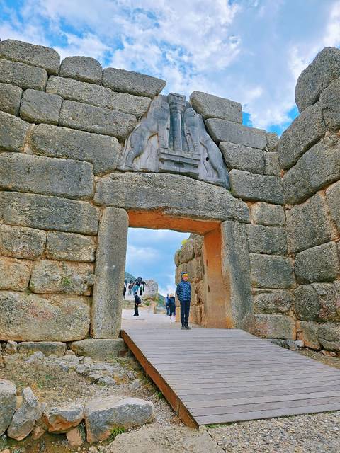 Stone gateway with historical carvings and people walking through.