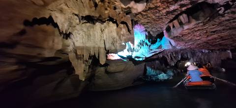 Boat tour inside a cave with colorful lighting