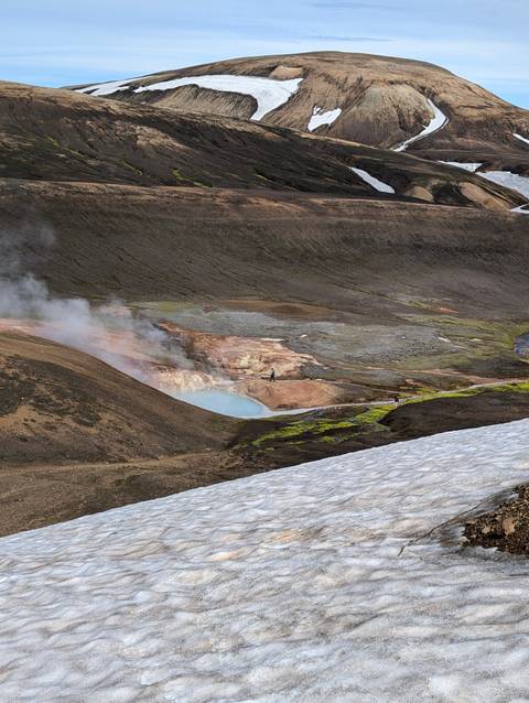 Geothermal area with colorful minerals and steam.