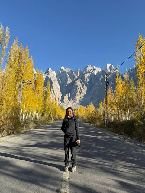 Person standing on a road with a backdrop of tall spiky peaks.