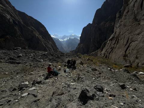 Hikers in a rocky valley with snow-capped peaks in the distance.