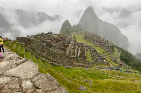 Machu Picchu ruins with misty mountains in the background.