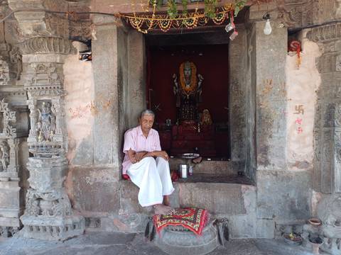 Man seated at temple entrance.