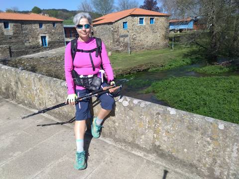 A hiker resting on a stone bridge.