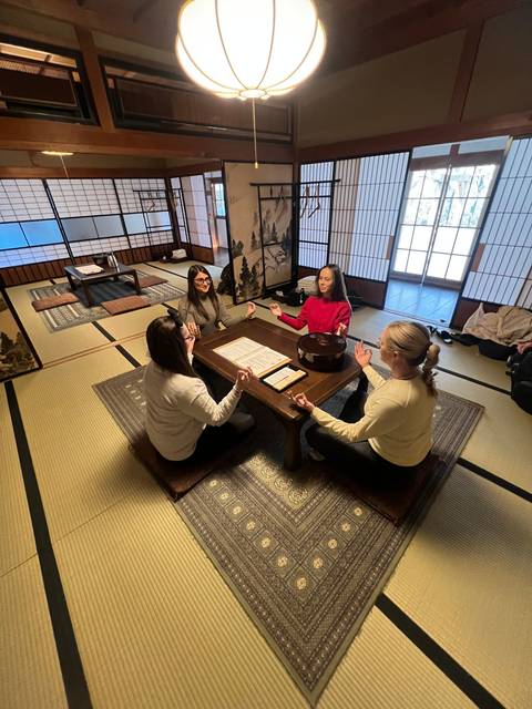       Four people sitting around a low table in a traditional Japanese room.
  
