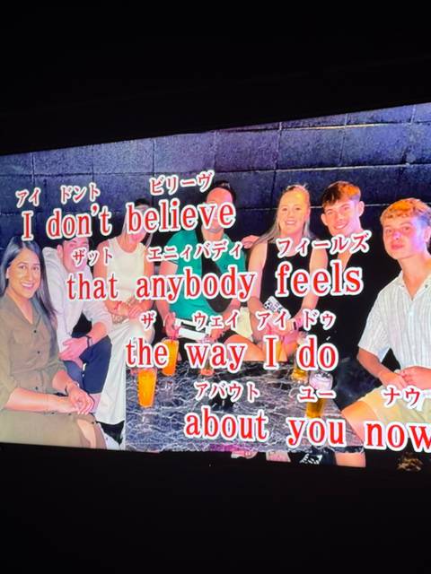       Group of people with text overlay in a karaoke setting.
  