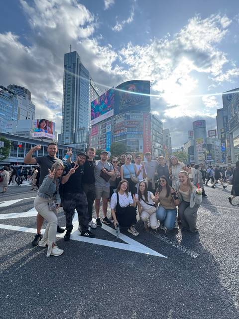       Group of people posing on a busy city street with tall buildings.
  