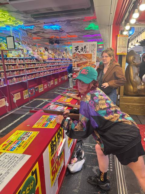       Person playing a shooting game at an indoor amusement venue.
  
