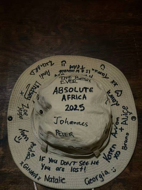 A hat with writings, 'Absolute Africa 2025', placed on a wooden table.