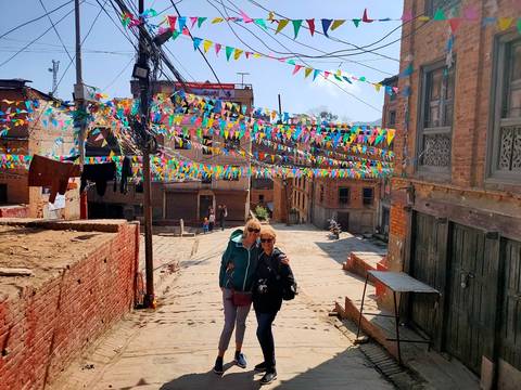Two people posing on a street festooned with colorful flags.