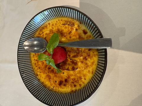      A dish of crème brûlée with a garnish on a plate.
  