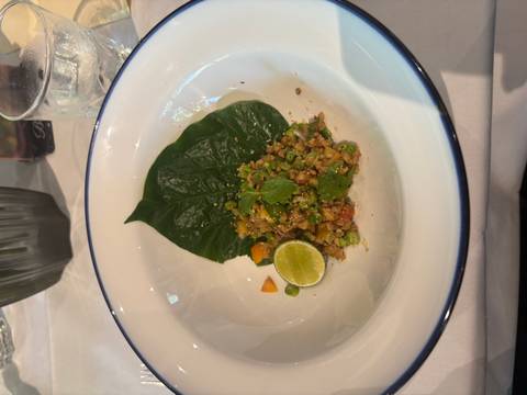       A dish of mixed vegetables and herbs served on leaves.
  